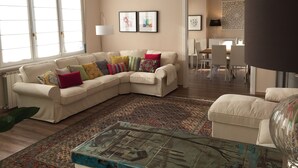 A living room with a beige sectional sofa, colorful pillows, a patterned rug, and a glass coffee table. - Fabulous 200sqm bright, new apartment walking distance to Duomo and city centre (Firenze)