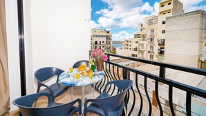 A balcony with a table set for breakfast, chairs, and a view of buildings and water. - Bugibba - 2 bedroom apt 150m from Sea Front Fully Air Conditioned, Terraces WiFi (Bugibba,)