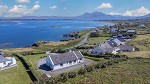 A coastal village with houses, a clear view of the sea, and a mountain in the background.