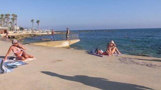 Ein Strand mit Menschen, die sich sonnen und schwimmen.