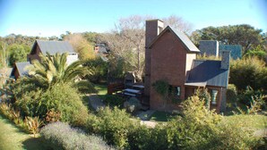 A residential property with a prominent brick house, a well-maintained garden, and a visible outdoor grill area. - Near Delmar (house 2) (Mar Azul)