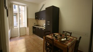A compact kitchen with dark cabinets, a dining table set with dishes, and a window overlooking a balcony. - apartment In the heart of Rome wonderful view front of the Colosseum discounts (Roma)