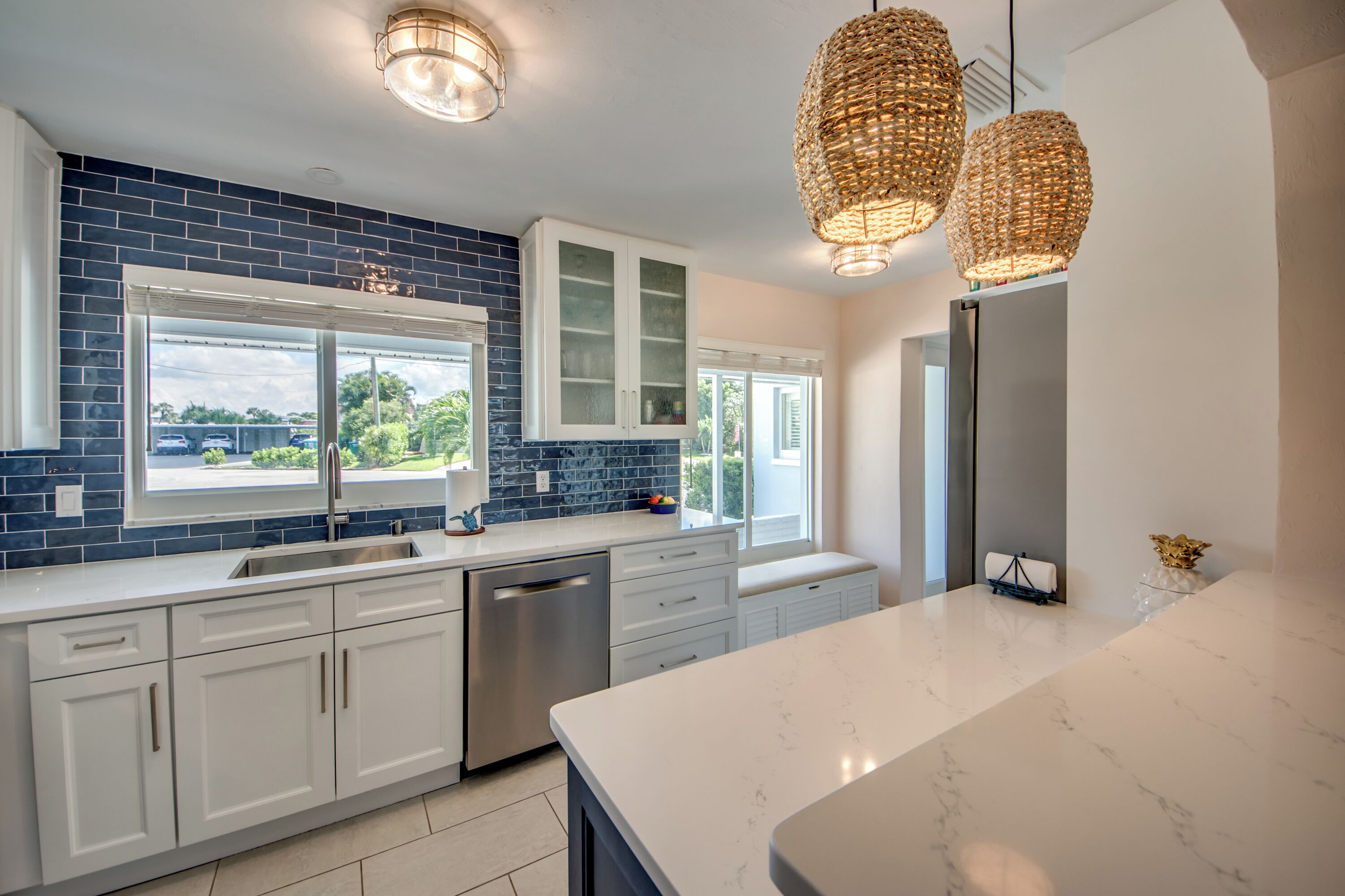 A modern kitchen with white cabinets, a stainless steel dishwasher, and a large island.