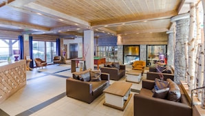 A spacious lobby with wooden beams, stone walls, and leather sofas.