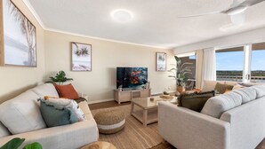 Un salon spacieux doté d’une grande fenêtre, d’un téléviseur à écran plat et d’un coin salon confortable.