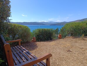 Un banco con vista a un paisaje costero, con una vista despejada del mar y colinas al distante.