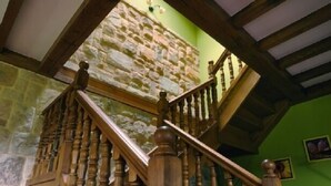 A wooden staircase with a stone wall background and a green wall to the right.