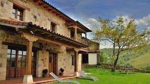 A stone house with a balcony, a lawn, and a picnic table.