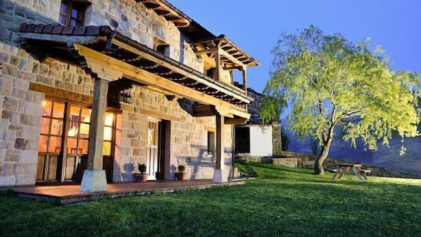 A stone building with a wooden porch and a tree in the background.