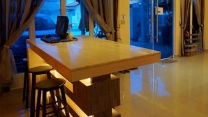 A modern kitchen with a wooden countertop, bar stools, and a built-in stove. - Tropical Villa Kuantan (Kuantan)