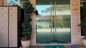 A building entrance with a glass door, a potted plant, and a row of lockers. - Tropical Villa Kuantan (Kuantan)