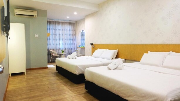 A hotel room with two beds, a desk, a chair, and an air conditioning unit. - Tropical Villa Kuantan (Kuantan)