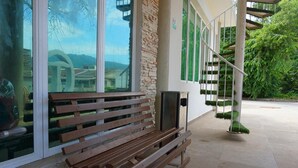 A wooden bench outside a building with large windows and a staircase. - Tropical Villa Kuantan (Kuantan)