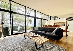 A modern living room with a sofa, a coffee table, and a view of the outdoors.