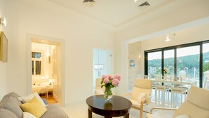 Una sala de estar moderna con sofá, sillones, una mesa de centro y vistas a un balcón con mesa y sillas.