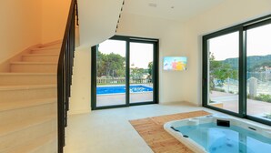 Un interior moderno con una escalera, un ventanal grande y una bañera de hidromasaje.