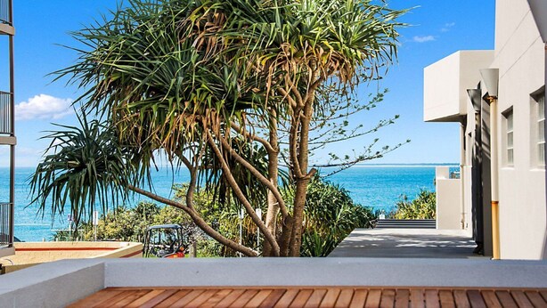 Ein modernes Gebäude mit einer Holzterrasse und Blick auf das Meer.