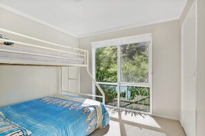 A room with a bunk bed, a window with a view of greenery, and a carpeted floor. - Christoe (Lorne)