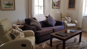 A living room with a sofa, armchairs, a coffee table, and a lamp.