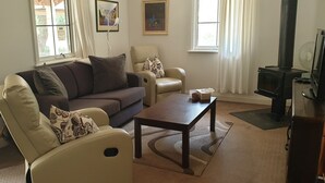 A living room with a sofa, armchairs, a coffee table, a fireplace, and a television.