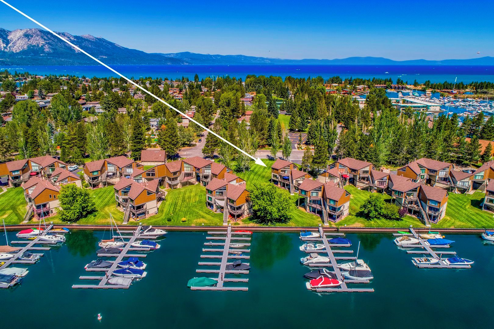 An aerial view of a residential area with houses, a marina, and a lake.
