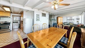A spacious living area with a wooden dining table, chairs, a fireplace, and a ceiling fan. - Rustic 6 Bedroom Cabin - Lakefront, Central in Town Location! (South Lake Tahoe)