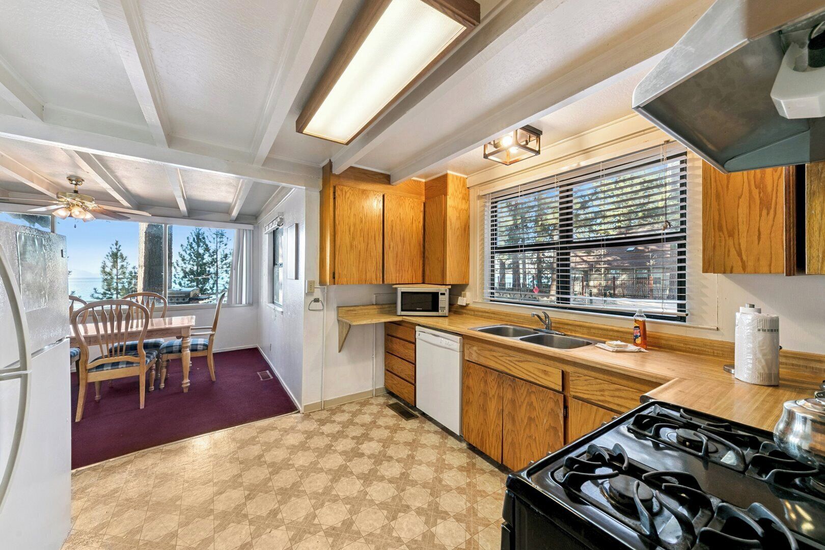 A compact kitchen with wooden cabinets, a microwave, a sink, and a stove.