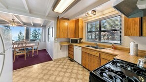 A compact kitchen with wooden cabinets, a microwave, a sink, and a stove. - Rustic 6 Bedroom Cabin - Lakefront, Central in Town Location! (South Lake Tahoe)