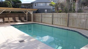 Relax by the pool surrounded by a shaded pergola and lounge chairs.