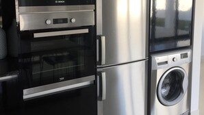 Eine moderne Küche mit Edelstahl-Kühlschrank, Backofen, Mikrowelle und integriertem Waschmaschine.