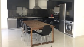 Eine moderne Küche mit Holztisch und Stühlen, einem eingebauten Backofen und einer Waschmaschine.