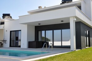 A modern house with a swimming pool, large sliding glass doors, and a minimalist design. - Luxury villa with private pool near Nazaré (Familiacao Nazare)