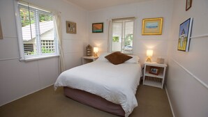 A bedroom with a bed, bedside tables, and a window with blinds.