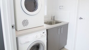 A compact laundry area with a washing machine, dryer, and sink.