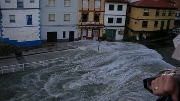 A view of a river with turbulent water, a railing, and buildings in the background.