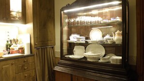 Cozinha com armários de madeira, uma vitrine de vidro com louças e uma geladeira.