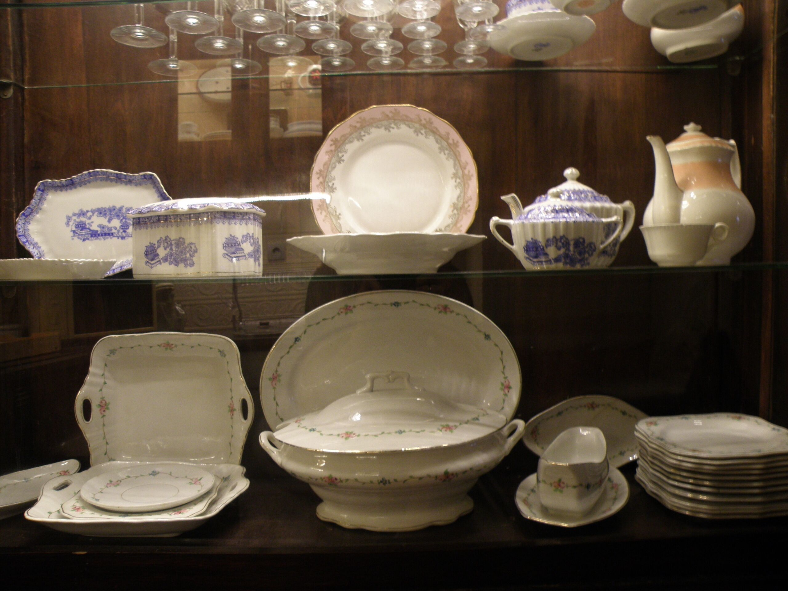 A display of white and blue patterned china, including plates, bowls, and teapots, arranged on shelves.