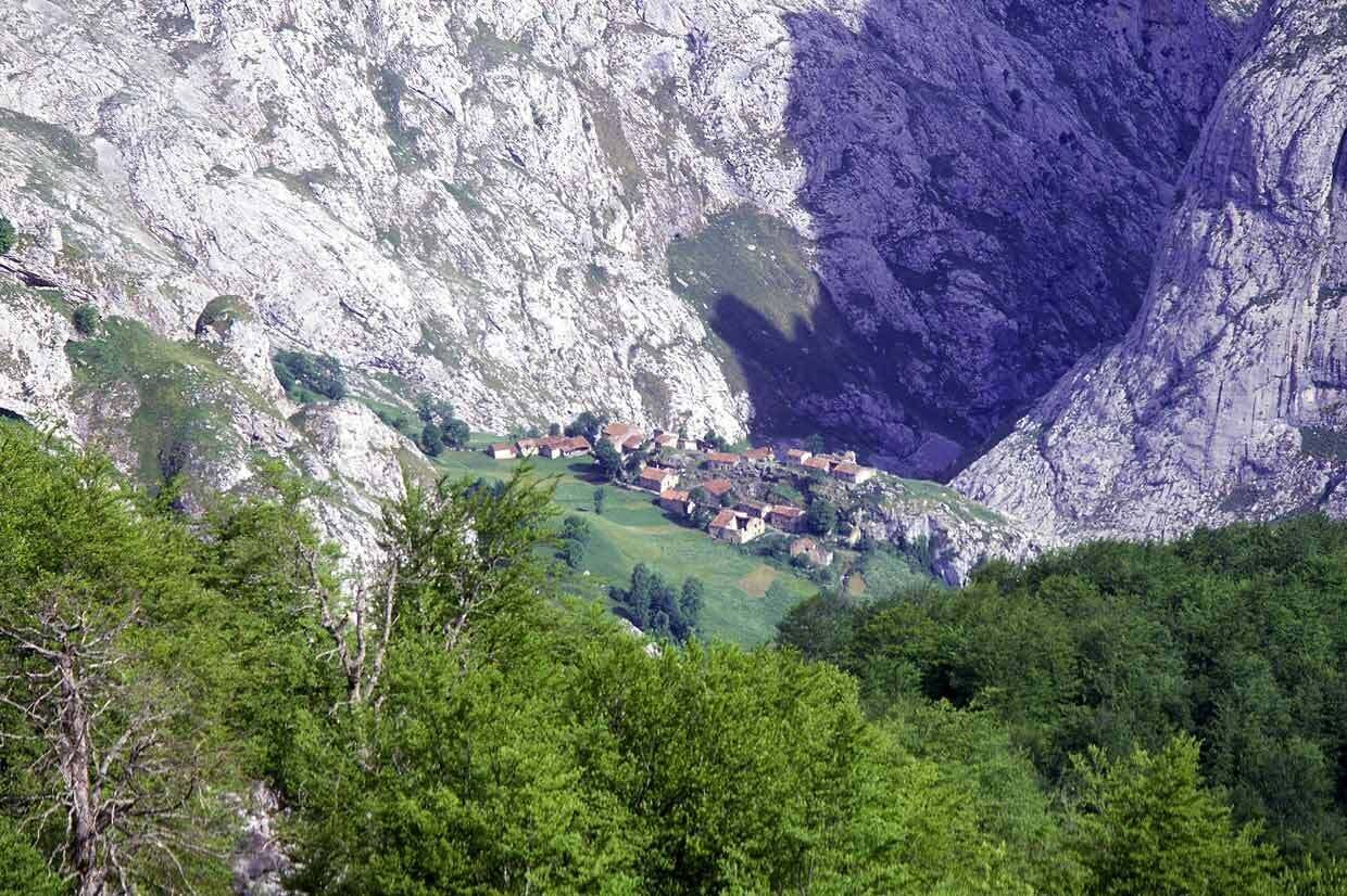 A village nestled in a valley with a steep cliff face.