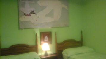 A hotel room with two beds, a nightstand with a lamp, a framed picture on the wall, and a large abstract painting above the beds.