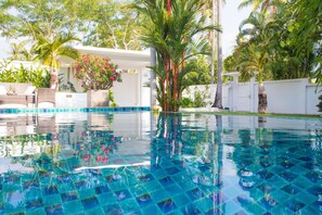 A clear blue pool with a tiled bottom, surrounded by lush greenery and palm trees. - Blissful Tropical Stay at SeaLaVie Villa (Rawai)