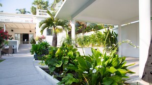 Un espace extérieur abrité, agrémenté de jardinières, d’un coin salon et d’un escalier menant à l’entrée d’un bâtiment.