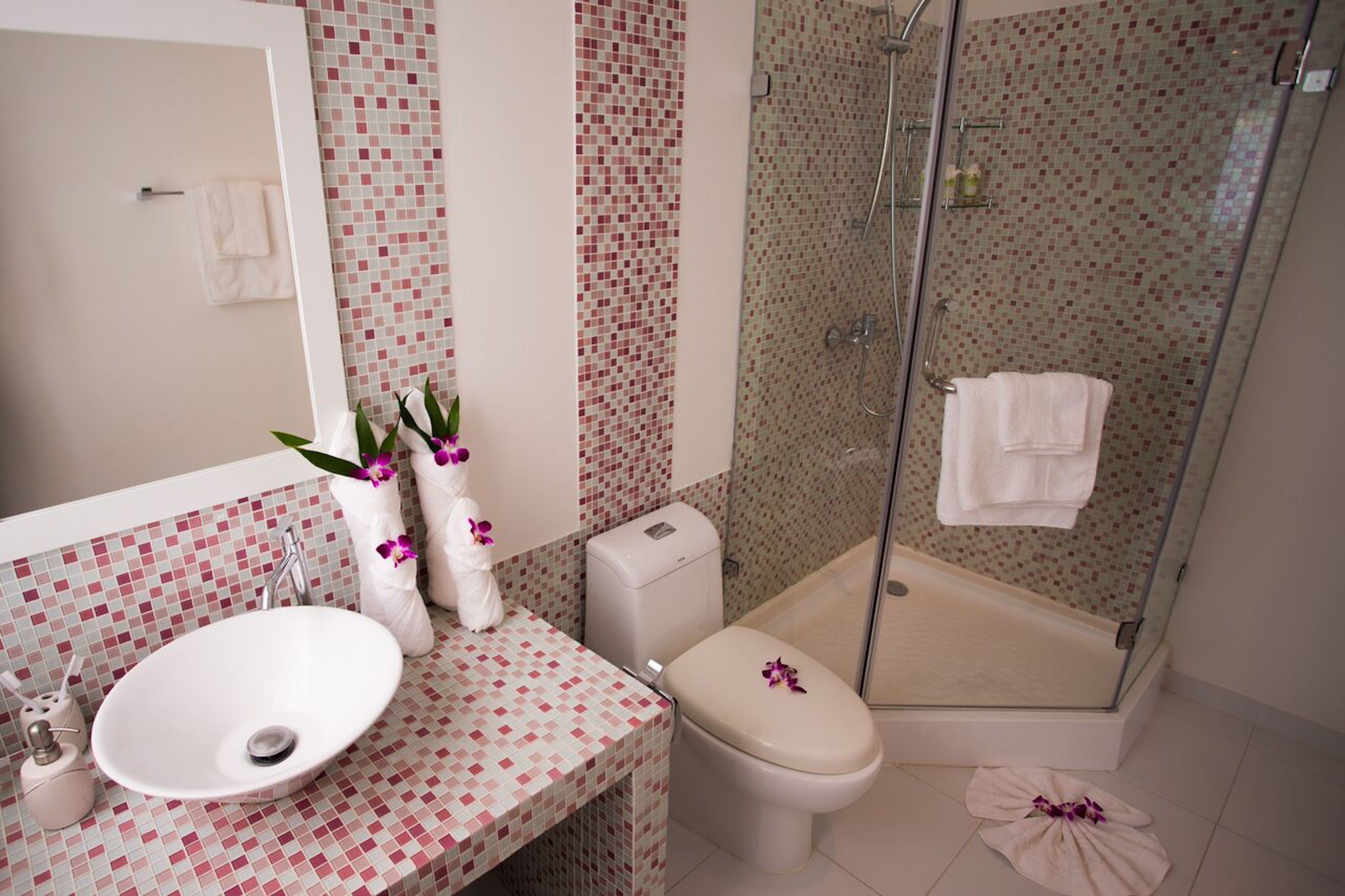 Une salle de bain avec un lavabo blanc, des toilettes et une douche à parois de verre.