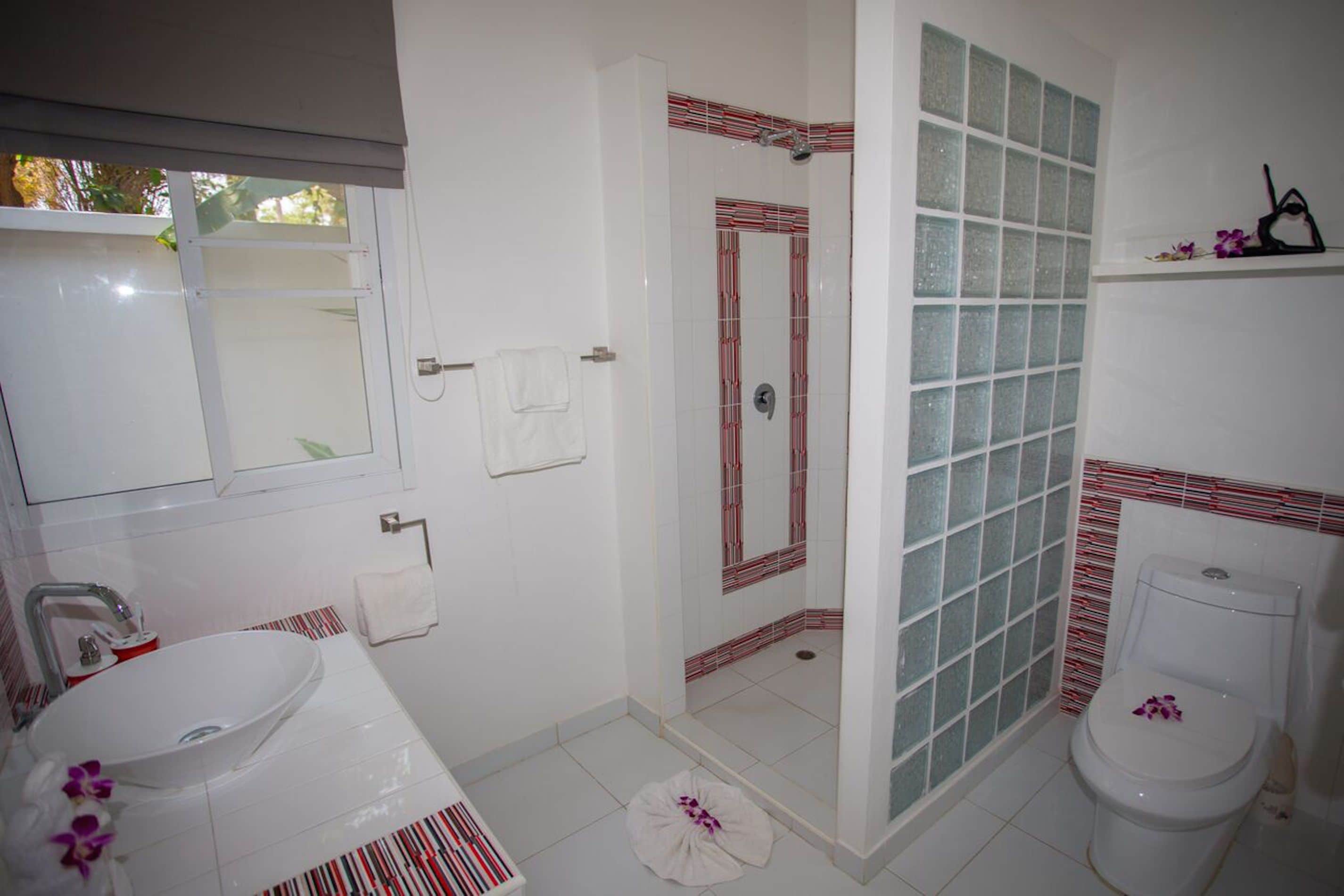 A bathroom with a white sink, a glass shower enclosure, and a toilet.