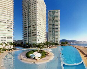 A resort with a large swimming pool, high-rise buildings, and a beach view. - Beachfront condo amazing views Peninsula PV (Puerto Vallarta)