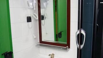 Un baño con un lavabo blanco, un espejo, un calentador de agua Bosch y una ducha con mampara de vidrio.