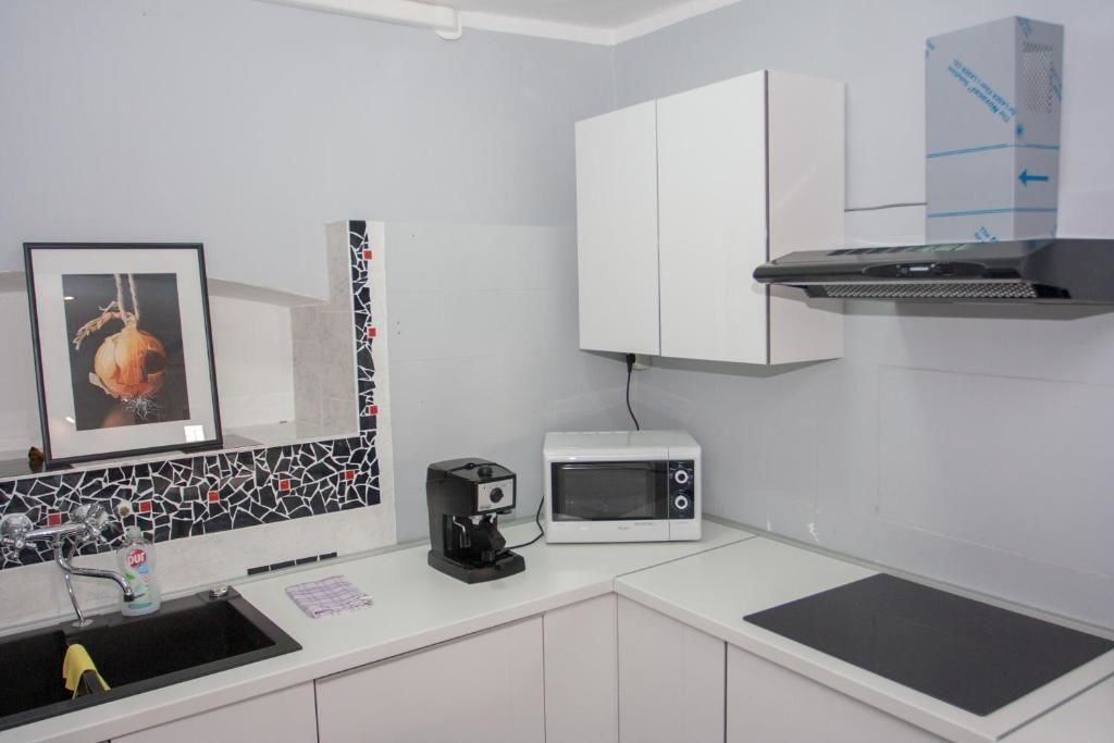 A modern kitchen with a microwave, coffee maker, and a sink.