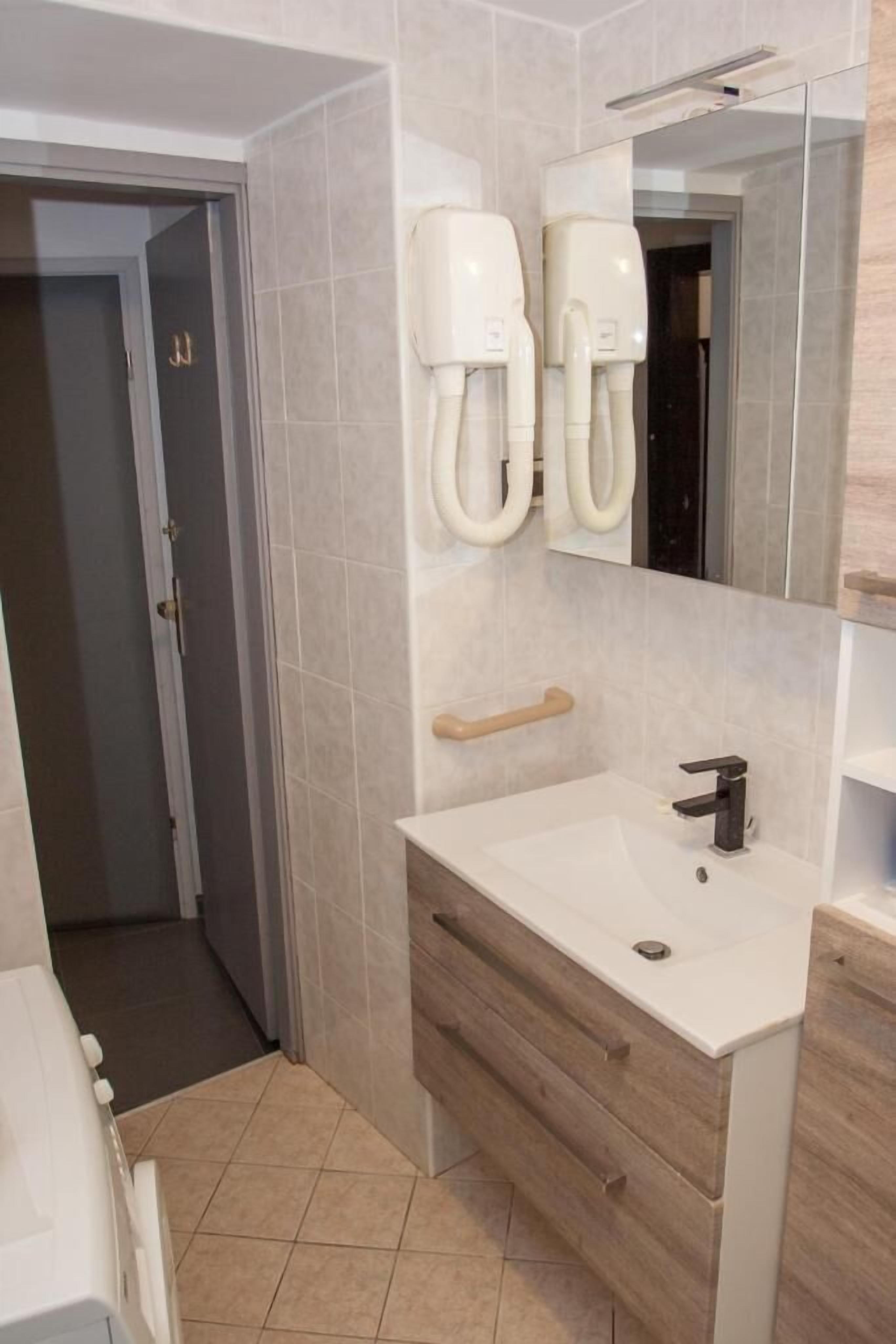 Une salle de bain avec un lavabo blanc, un meuble-lavabo en bois et un miroir au-dessus.