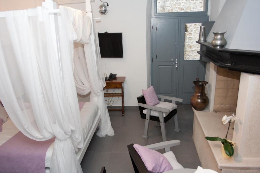 Un dormitorio con cama con dosel, un pequeño escritorio con silla, una chimenea y un televisor montado en la pared.