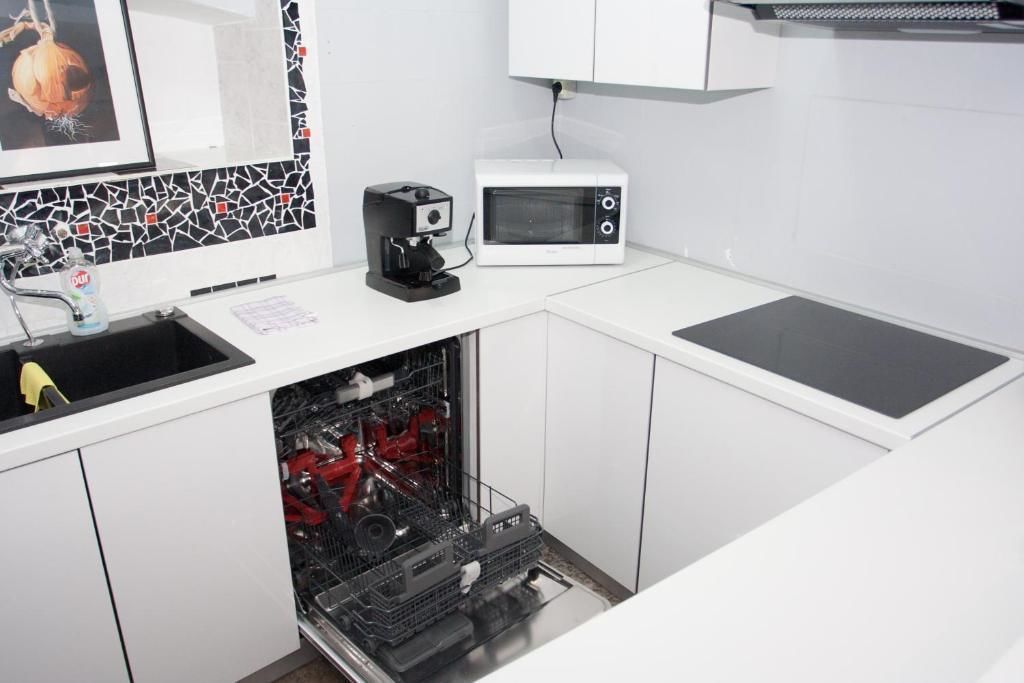 A compact kitchen with a dishwasher, a coffee maker, and a microwave.