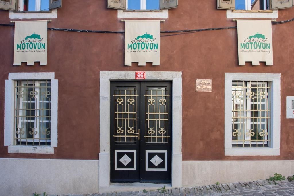 Een gevel met drie banners die 'Houses of MOTOVUN' accommodatie en catering adverteren.